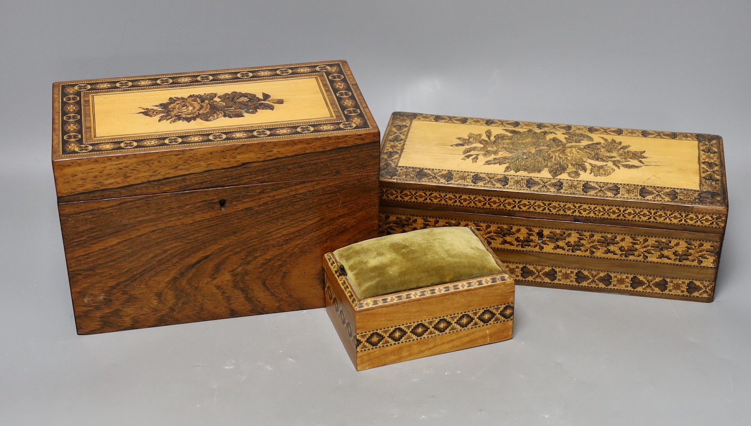 A selection of three Tunbridge ware boxes, to include a rosewood tea caddy, an unusual olivewood fall front glove box and a cushion top sewing box, Tallest 14cm